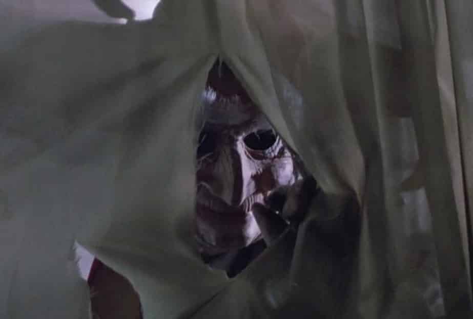 Jester's face poking through a torn sheet